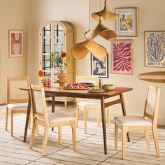 a dining room table with chairs and art on the wall