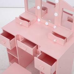 a pink dressing table with drawers and mirror