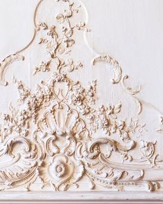 an intricately carved white paneled wall with flowers and leaves on it's side