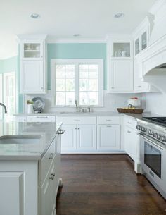 a kitchen with white cabinets and wood floors