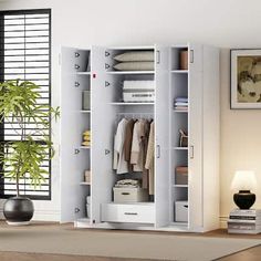 an open closet with clothes hanging on the doors and shelves next to a potted plant