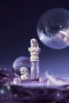 a purple liquid bottle with bubbles in the background and an angel figurine next to it