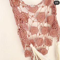 a pink crocheted shawl with tassels hanging from it