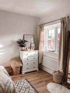 a white dresser sitting next to a window in a bedroom