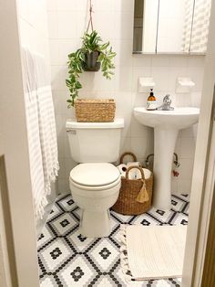 a white toilet sitting in a bathroom next to a sink and a basket on the floor