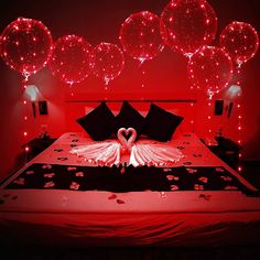 a bed with two swans made out of paper towels on it and some balloons in the background