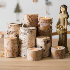 several birch logs stacked on top of each other next to a statue and candle holder