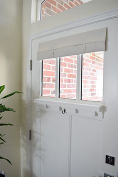 a white door with two windows and a potted plant