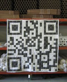 an image of a qr code quilt displayed on a shelf in a storeroom