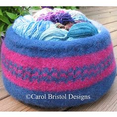 a blue, pink and purple knitted basket sitting on top of a wooden table