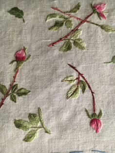 some pink flowers and green leaves on a white cloth