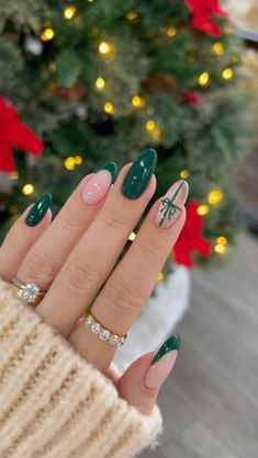 a woman's hand with green and white nail polish on it, next to a christmas tree