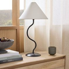 a table lamp sitting on top of a wooden dresser next to a bowl of fruit