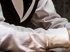 a man in a suit and tie sitting at a desk with his hand on the keyboard