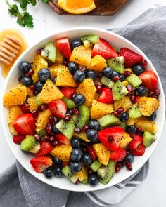 a white bowl filled with fruit next to sliced oranges