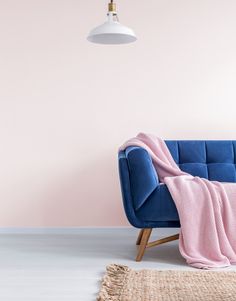 a blue couch with a pink blanket sitting on top of it next to a lamp