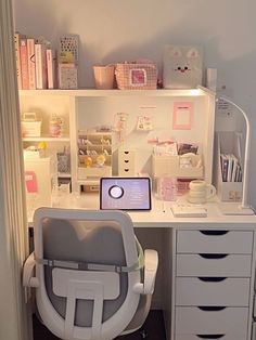 a white desk with a laptop computer on top of it next to drawers and shelves