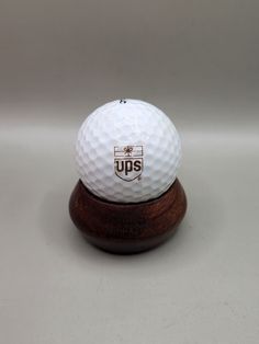 a white golf ball sitting on top of a wooden stand with the ups logo on it