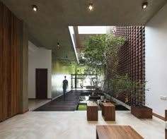 a man standing in the middle of a room next to a wall with plants on it