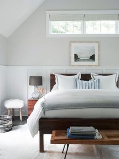 a large bed sitting under a window in a bedroom next to a table with two lamps on it