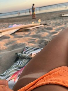 a woman laying on top of a beach next to surfboards