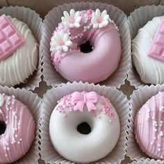 six pink and white donuts with frosting on them in paper trays next to each other