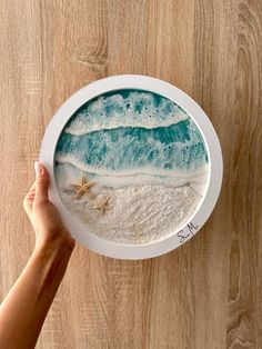 a hand holding a plate with an image of the ocean and starfish on it