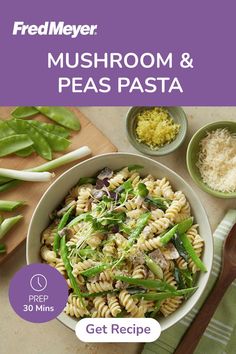 a bowl of pasta with green beans and other ingredients on the table next to it