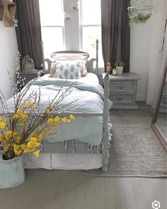 a bedroom with a bed, dresser and yellow flowers in vases on the floor