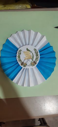 a blue and white paper fan sitting on top of a green table next to a pair of scissors