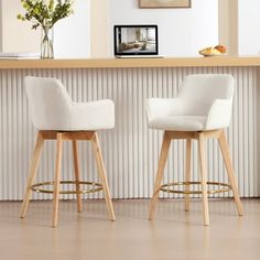 two white chairs sitting next to each other in front of a counter