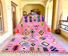 a man sitting on top of a pink rug covered in squares and rectangles