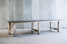 two wooden tables sitting next to each other in front of a wall with concrete panels