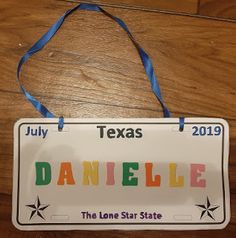 a sign that says danielle on it hanging from a wooden floor with a blue ribbon