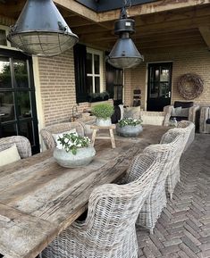 an outdoor dining table with wicker chairs and potted plants on the outside patio