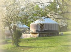 a large round structure sitting on top of a lush green field next to trees and bushes