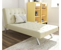 a white daybed sitting on top of a wooden floor next to a book shelf