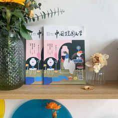 there are two books on the shelf with flowers in vases next to each other