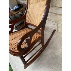 a wooden rocking chair sitting next to a stone wall