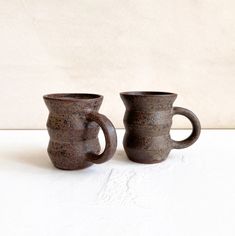 two brown mugs sitting next to each other on a table