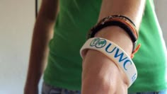 a close up of a person wearing a wristband with the word uwc on it