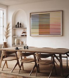 a dining room table with four chairs and a large painting on the wall above it