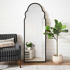 a living room with a chair, mirror and potted plant