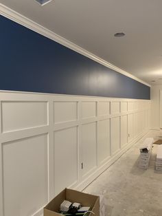 an empty room with blue and white paint on the walls, some boxes in the foreground