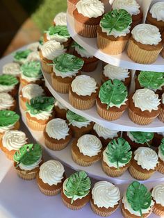 three tiered cupcake display with white frosting and green leaves on each tier