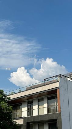 an apartment building with balconies and balconyes on the second floor, under a partly cloudy blue sky