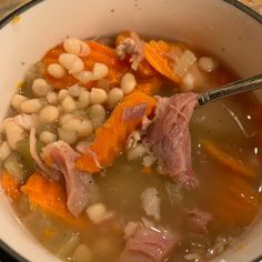 a bowl of soup with ham, beans and carrots