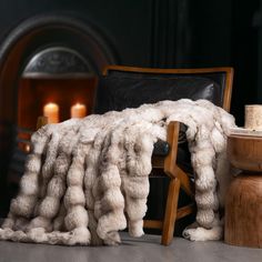 a chair with a fur blanket on it next to a table and candle lit candles