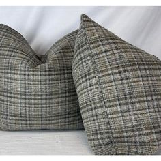 two gray and black plaid pillows sitting on top of a white bed sheet, one is facing the camera