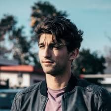 a man in a leather jacket is standing outside